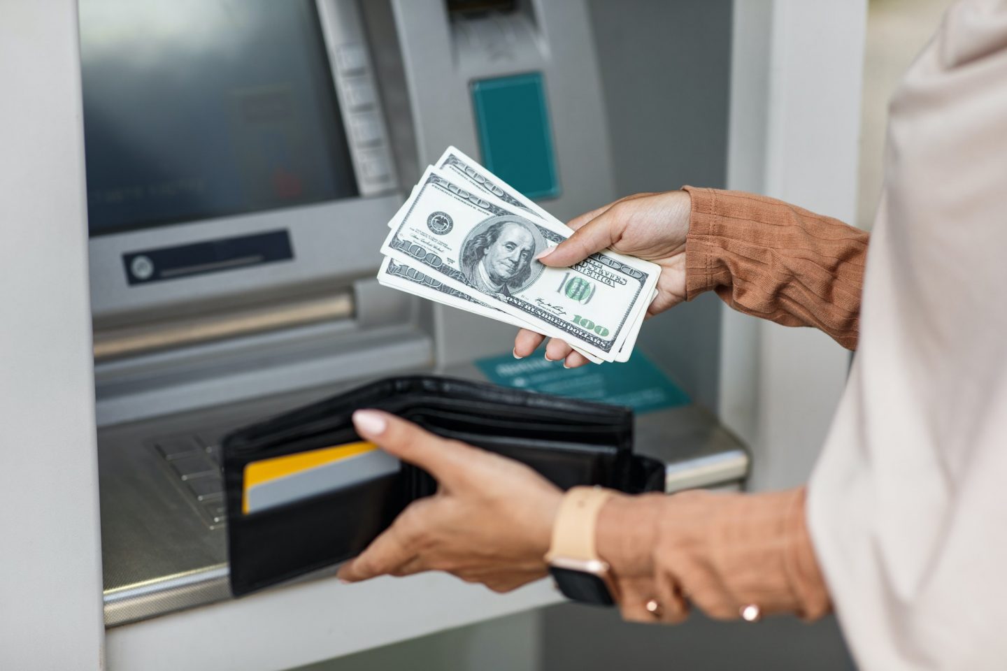 Young woman withdrawing money from credit card at ATM